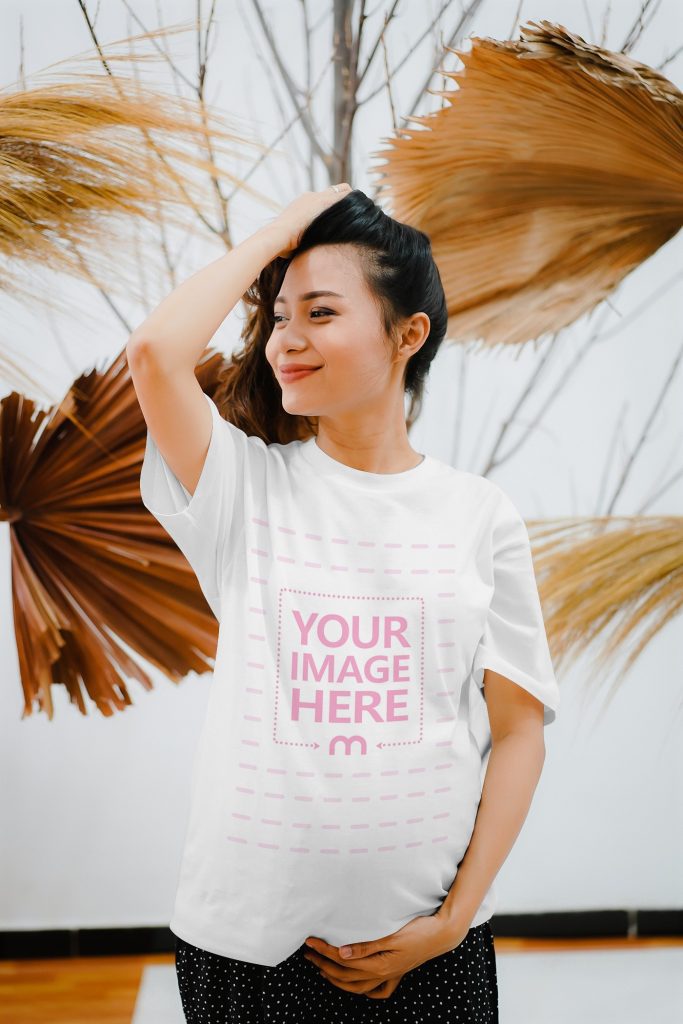 T-Shirt Mockup of a Pregnant smiling Woman in front of Some Dry Leaves
