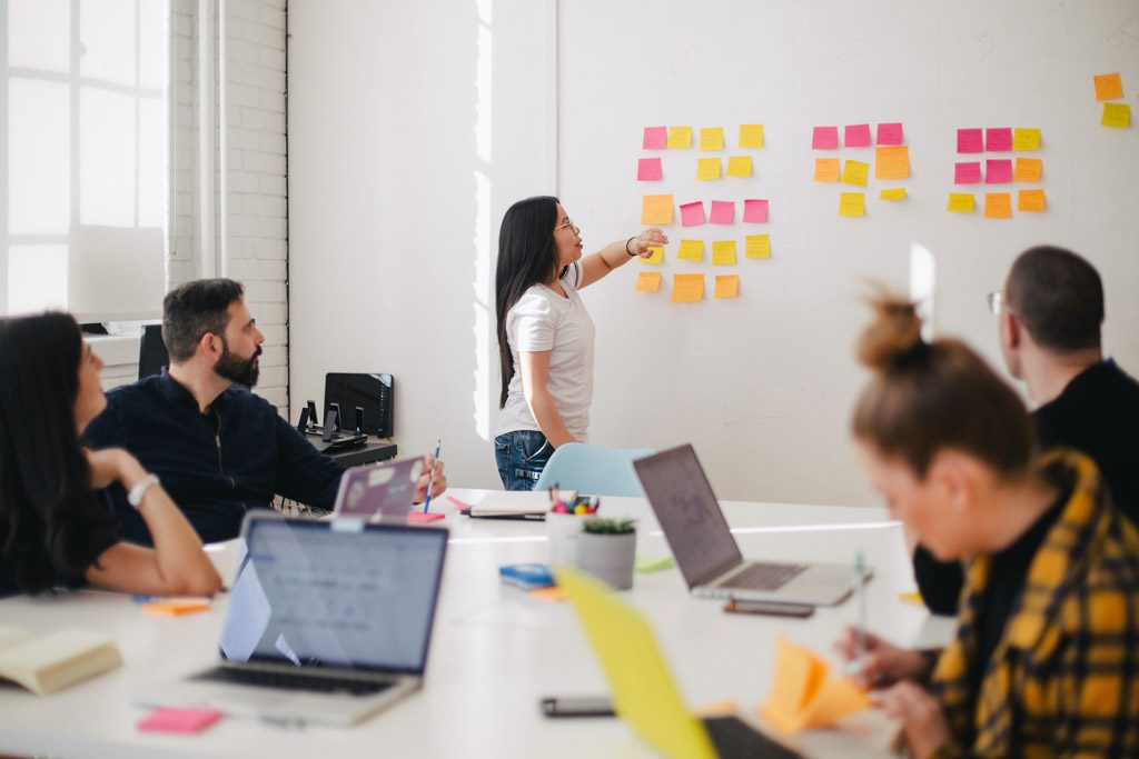 Woman explaining what's written on a post it note in a meeting about content creation